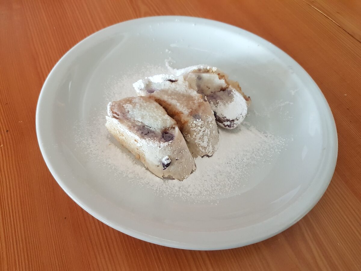 Sliced struklji, a rolled dough with a filling, dusted with sugar on a white plate