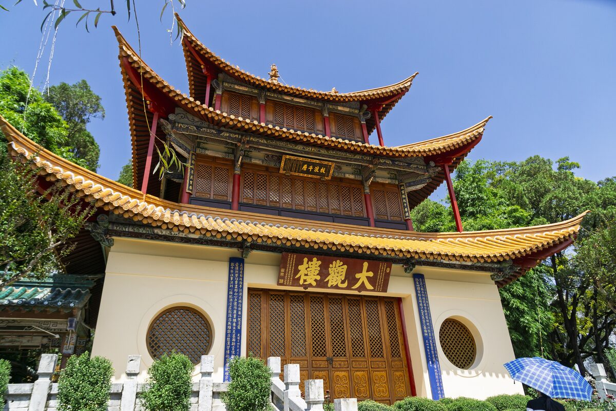 The three-storey Daguan Pavilion with golden tiled eaves and round windows under a blue sky