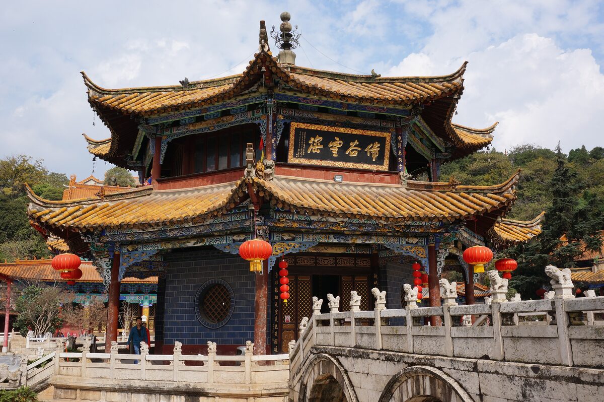 The two-tier octagonal pavilion of Yuantong Temple behind a white stone bridge, with red lanterns