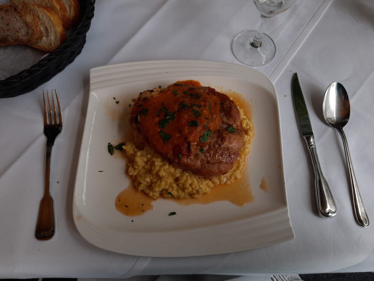 Braised veal shank with tomato sauce on saffron risotto, on a white plate