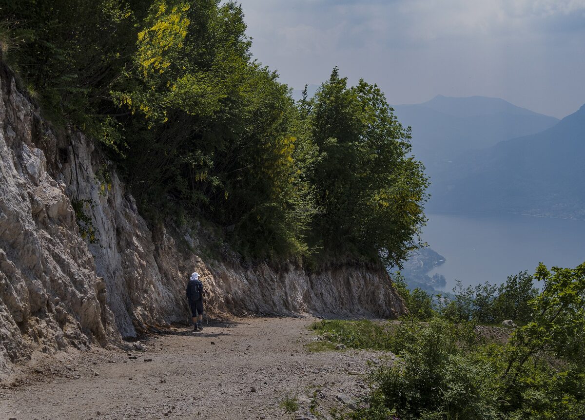 A rocky dirt path above the lake, with a walker on the trail