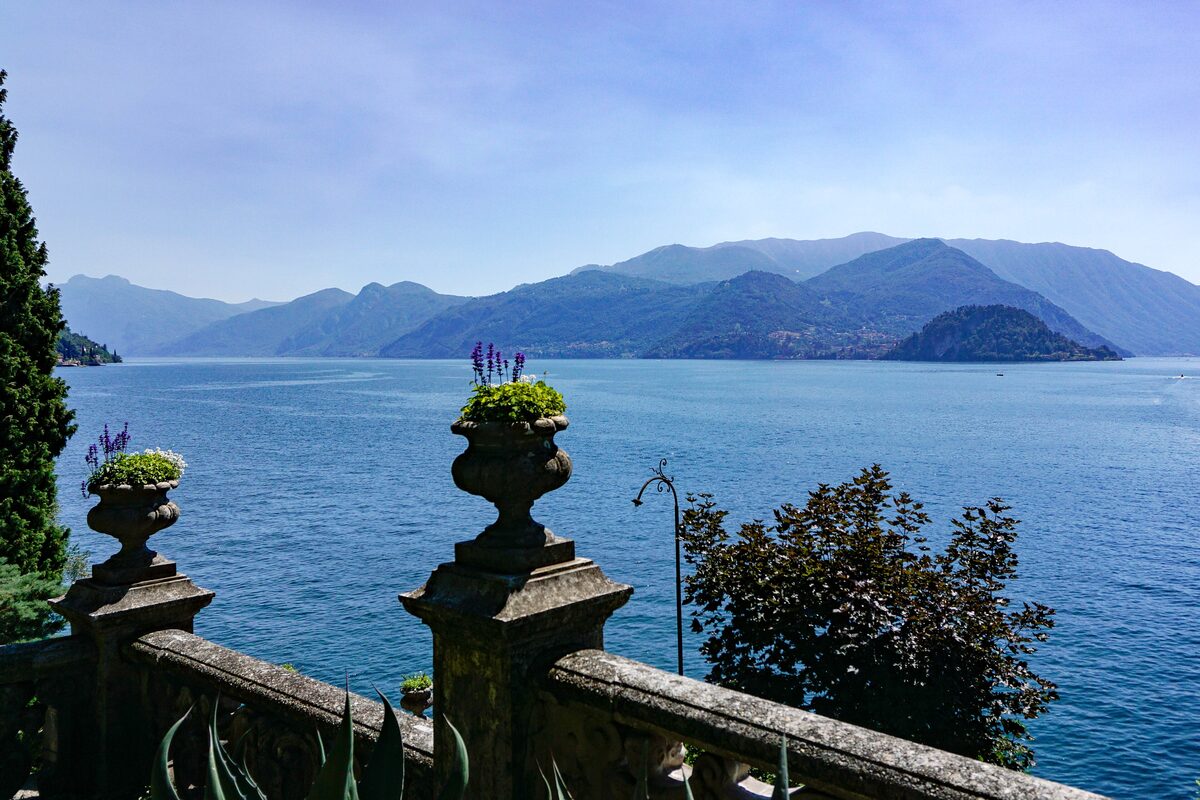 Stone urns with flowers on the balustrade of Villa Monastero, with the lake behind