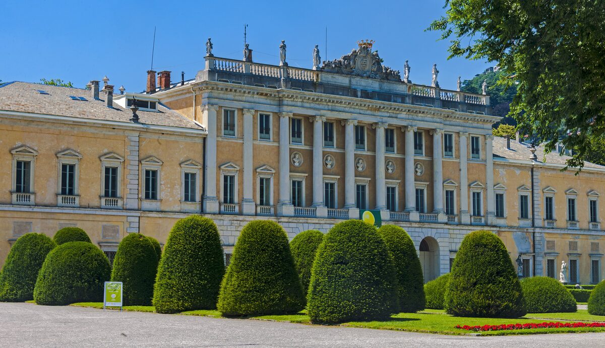 The yellow neoclassical front of Villa Olmo behind clipped topiary