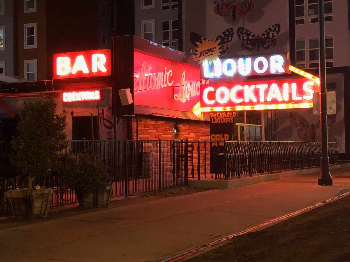The neon Atomic Liquors, Bar and Cocktails signs glowing red on the corner building at night