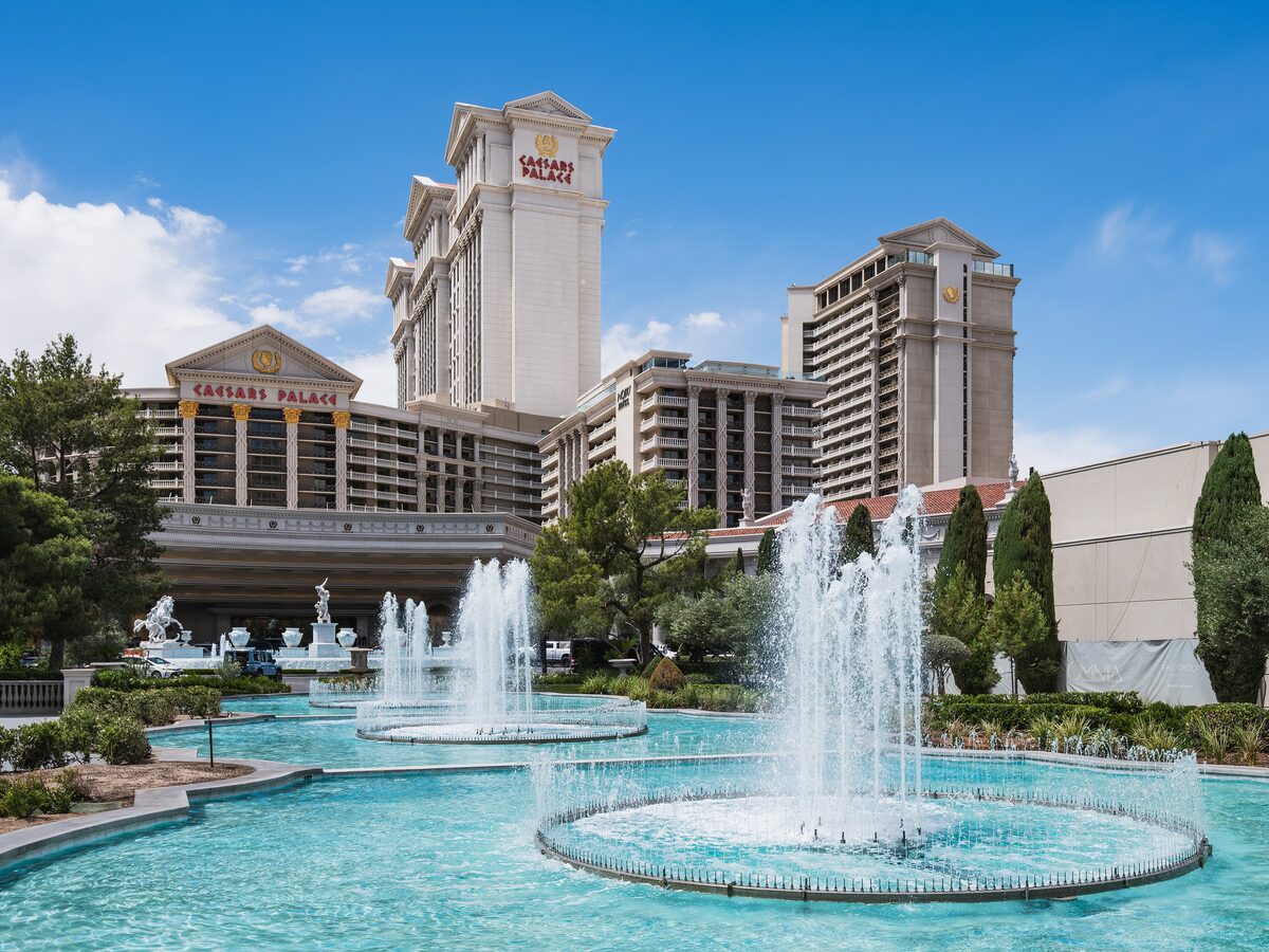 Caesars Palace hotel towers behind blue pools and fountains at the entrance on the Strip
