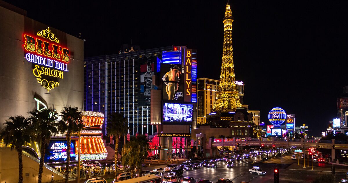 The Las Vegas Strip at night with the Paris Eiffel Tower, Bally's and Horseshoe signs and traffic on Las Vegas Boulevard