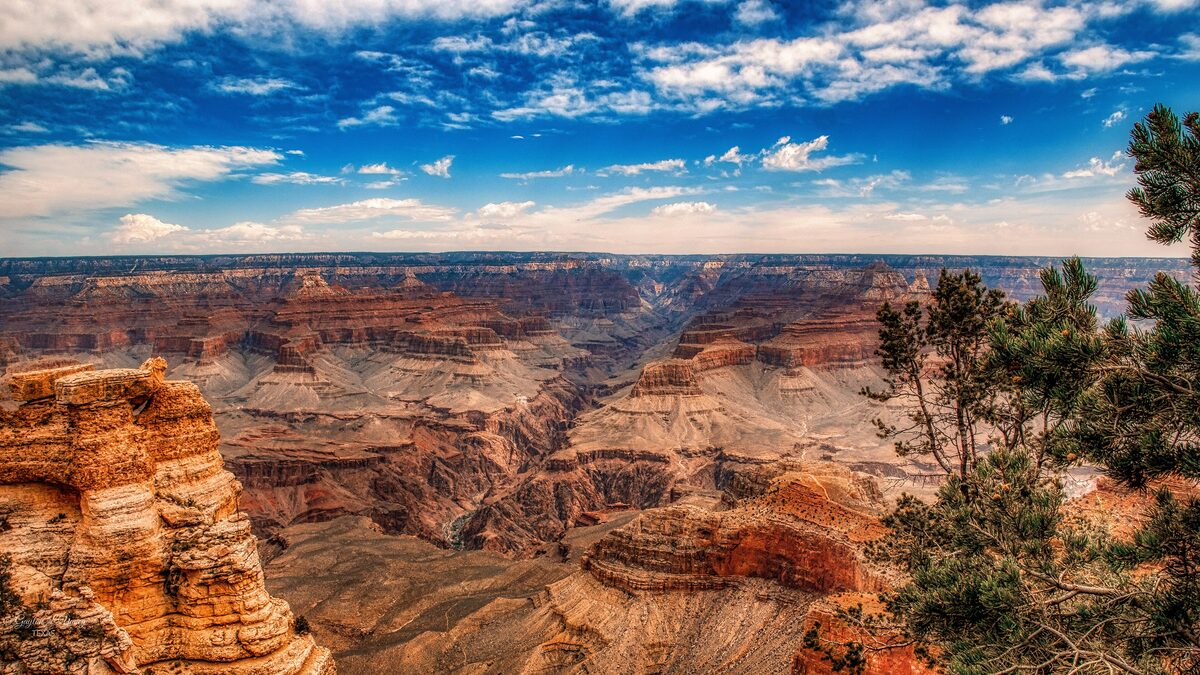 The Grand Canyon from Mather Point on the South Rim, with layered red cliffs and a blue sky
