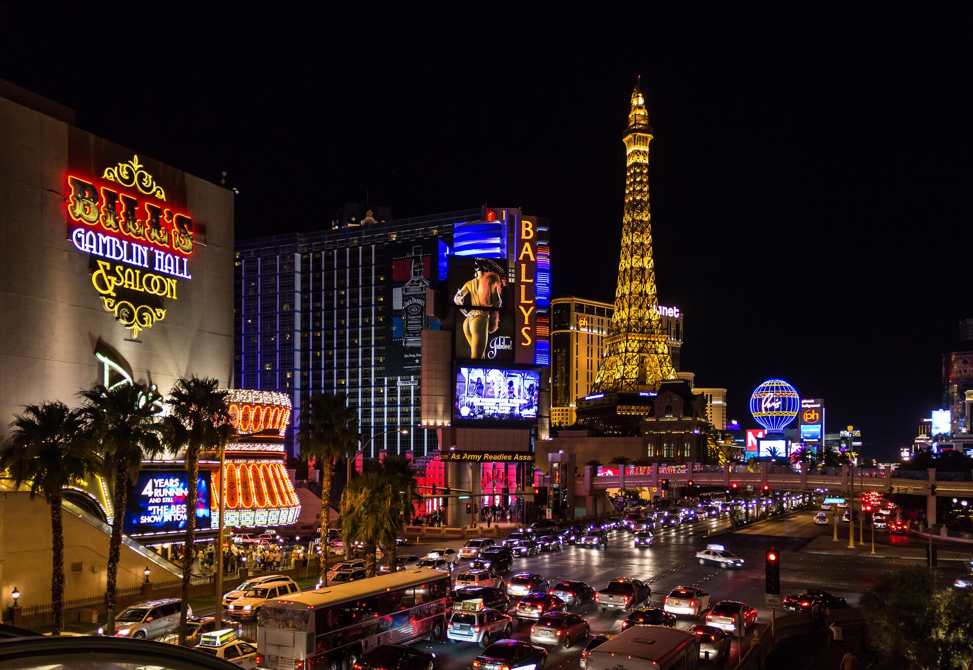 The Las Vegas Strip at night with the Paris Eiffel Tower, Bally's and Horseshoe signs and traffic on Las Vegas Boulevard