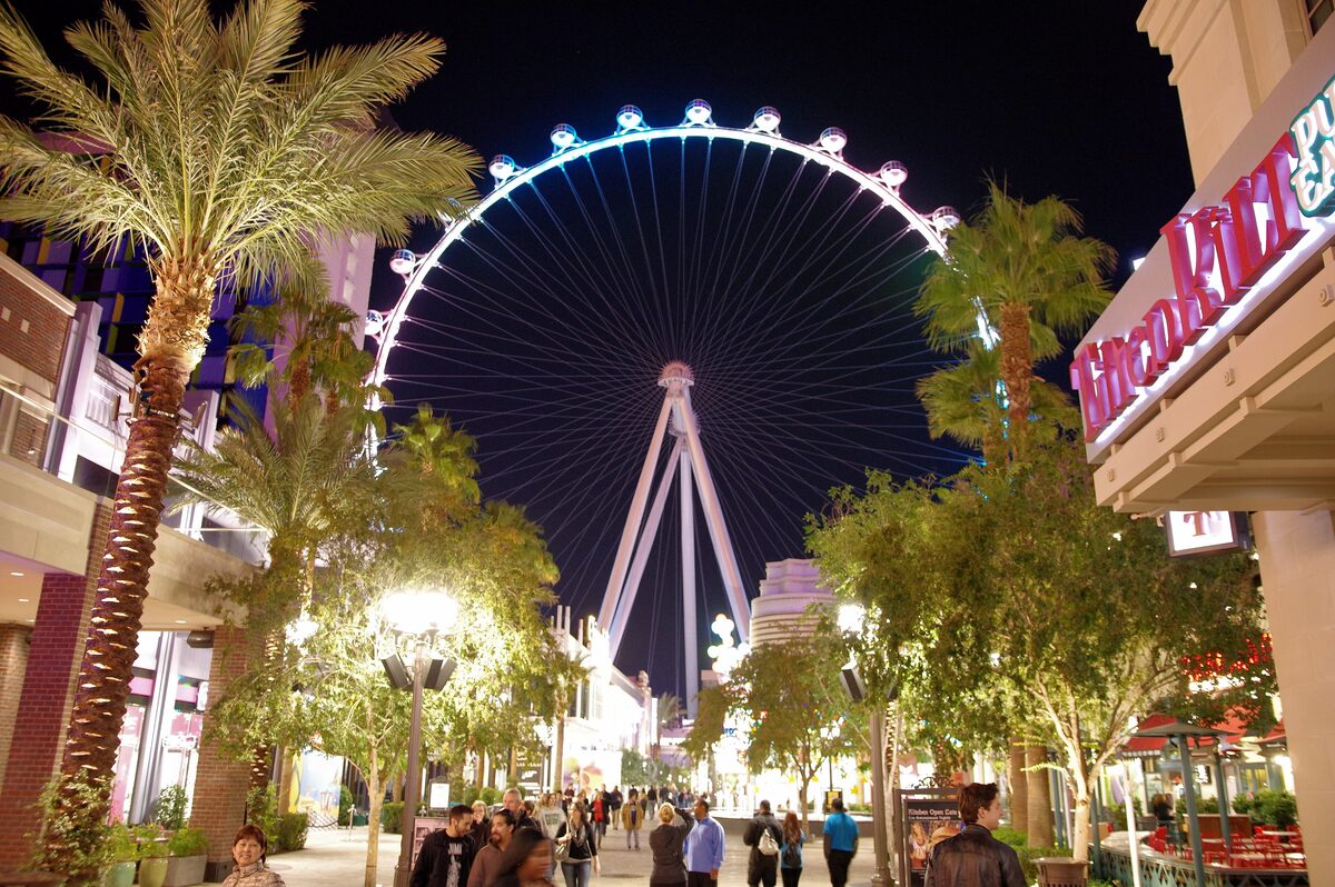 The High Roller observation wheel lit up at night above the palm-lined LINQ Promenade