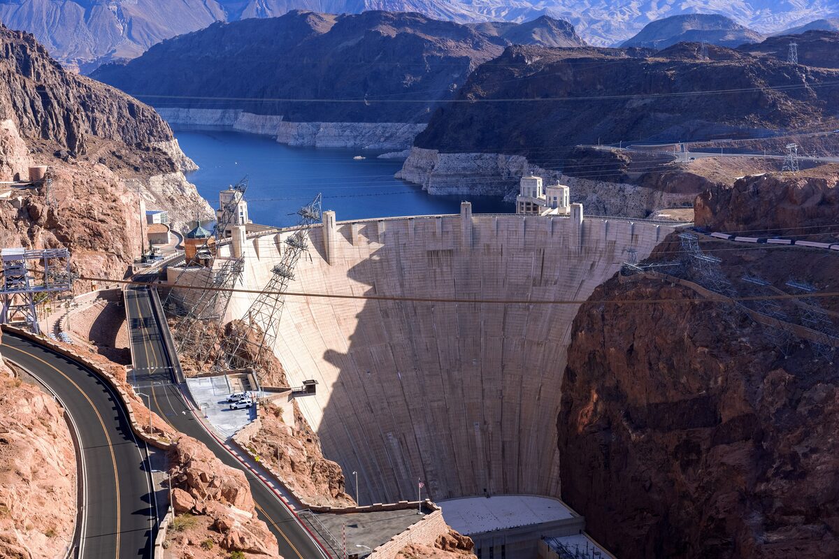 Hoover Dam in Black Canyon seen from above, with the road, intake towers and the Lake Mead bathtub ring