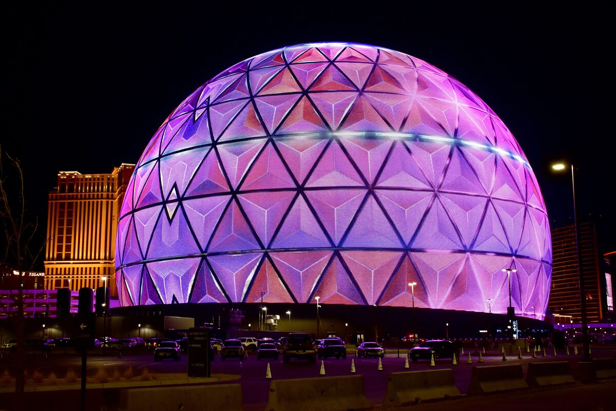 The Sphere at night, its LED skin lit in pink and purple triangles