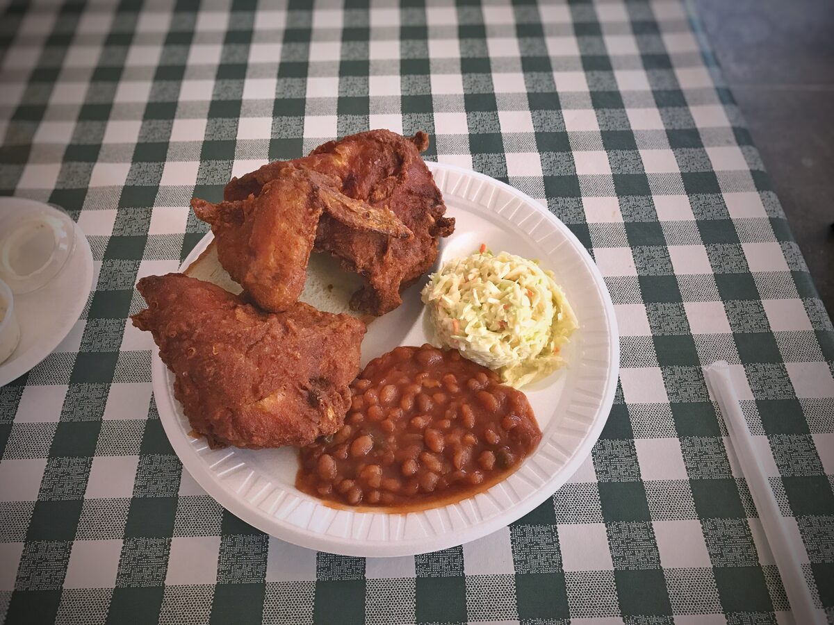 Fried chicken, baked beans and coleslaw on a paper plate