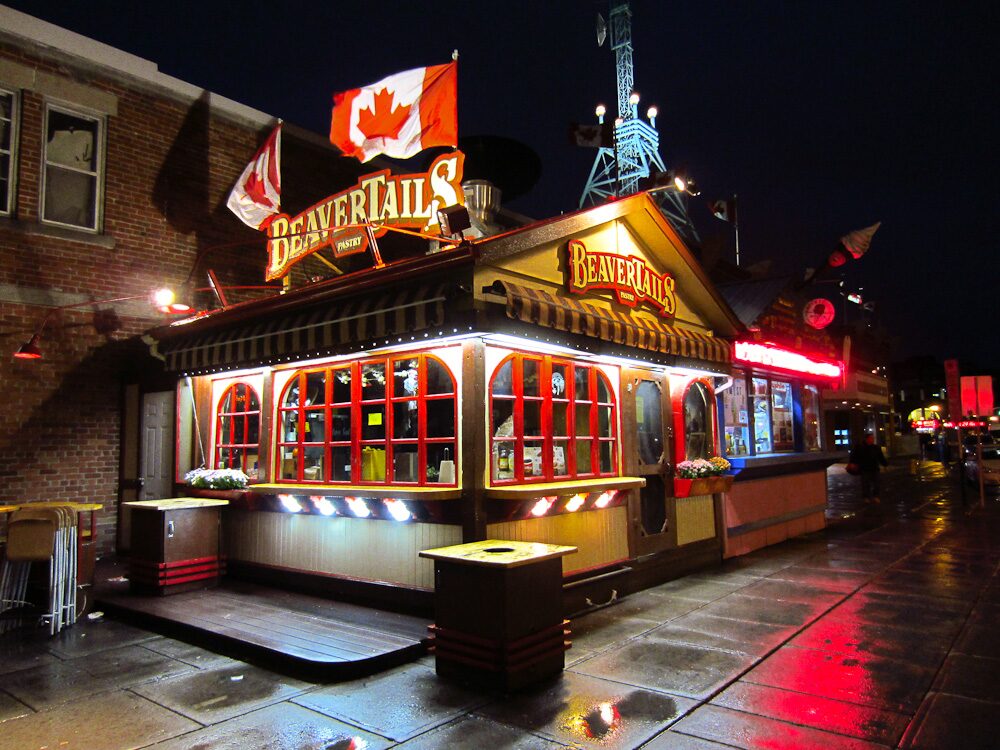 A BeaverTails pastry shop lit up at night, with the red maple-leaf sign above the windows (the Ottawa Byward Market branch)