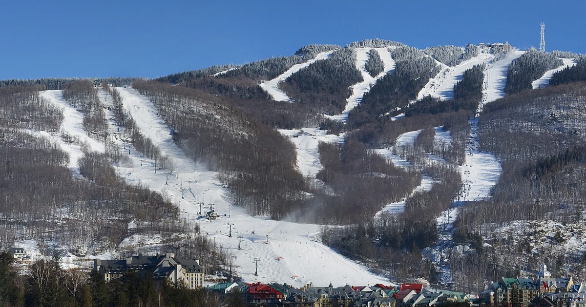 Snow-covered ski slopes of Mont Tremblant on a clear winter day, with the pedestrian village at the foot of the mountain