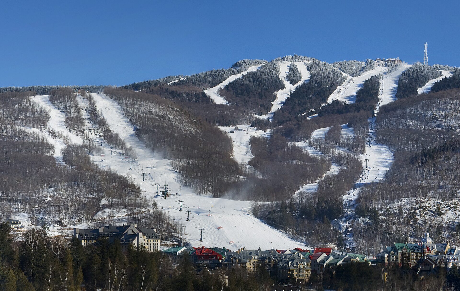 Snow-covered ski slopes of Mont Tremblant on a clear winter day, with the pedestrian village at the foot of the mountain