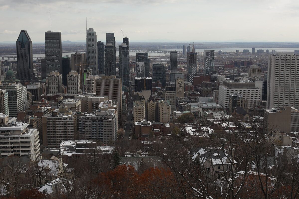 The downtown Montreal skyline in winter, seen from Mount Royal over bare trees and light snow