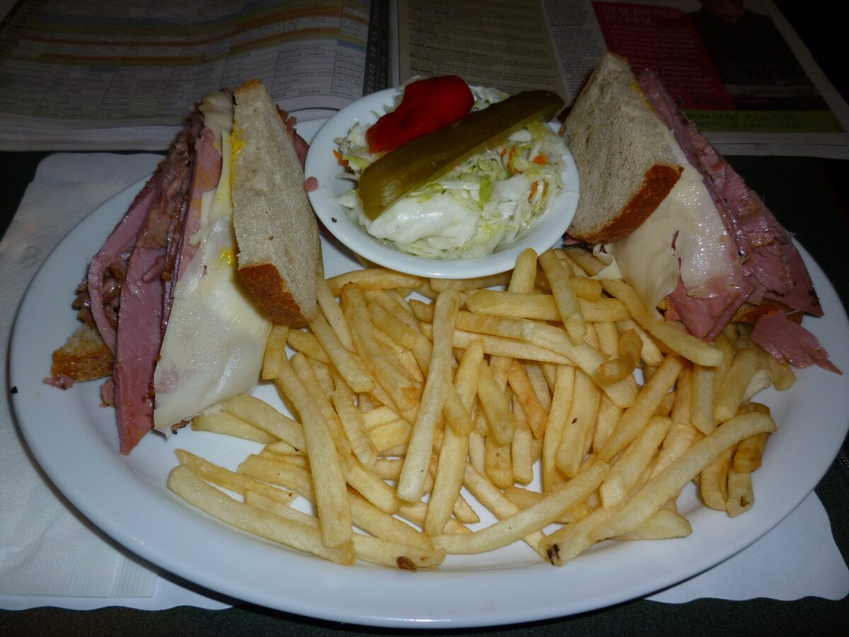 A Montreal smoked meat sandwich on rye with coleslaw, a pickle and french fries