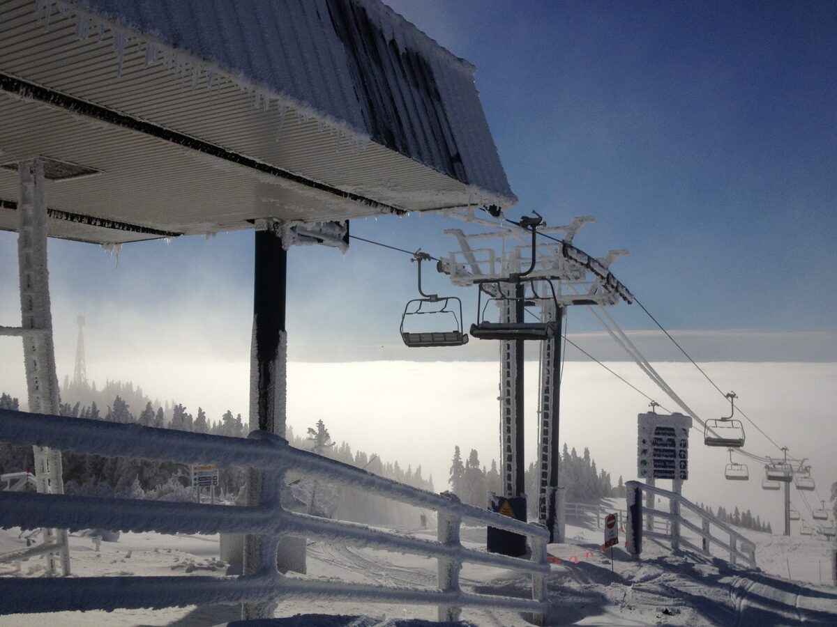 A chairlift line at the summit of the Soleil side of Mont Tremblant, with snowy trees and a sea of cloud below
