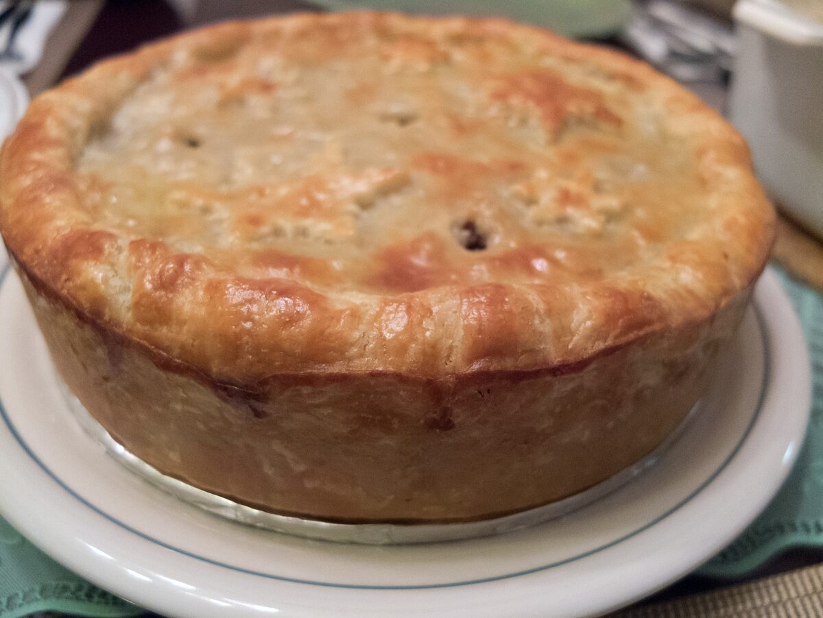 A whole golden tourtiere, the Quebec meat pie, on a plate