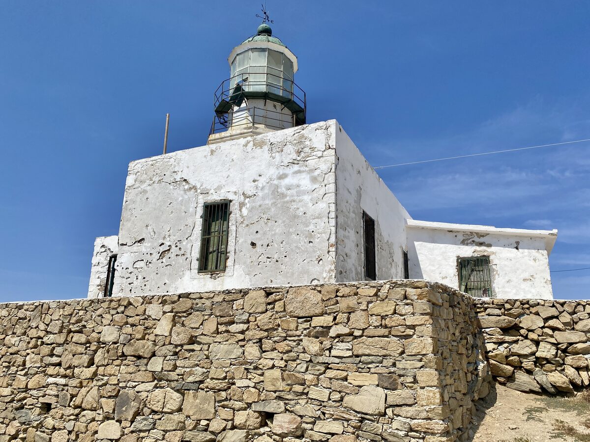 The whitewashed Armenistis lighthouse on its stone base, under a clear blue sky