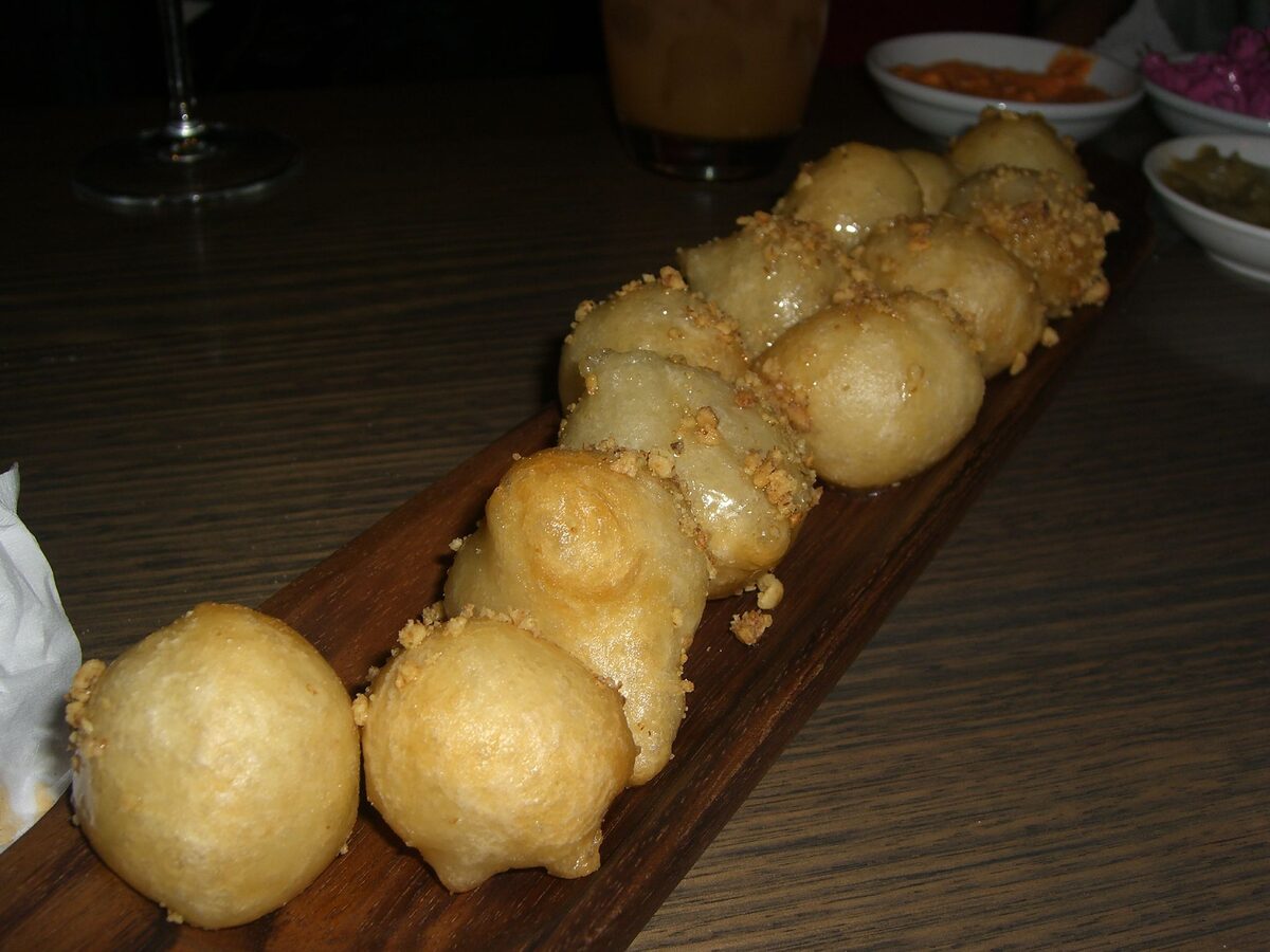 Fried loukoumades dough balls with walnuts on a wooden board