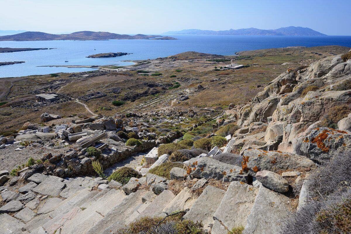 Stone steps climbing the bare rocky slope of Mount Kynthos on Delos, with the sea beyond
