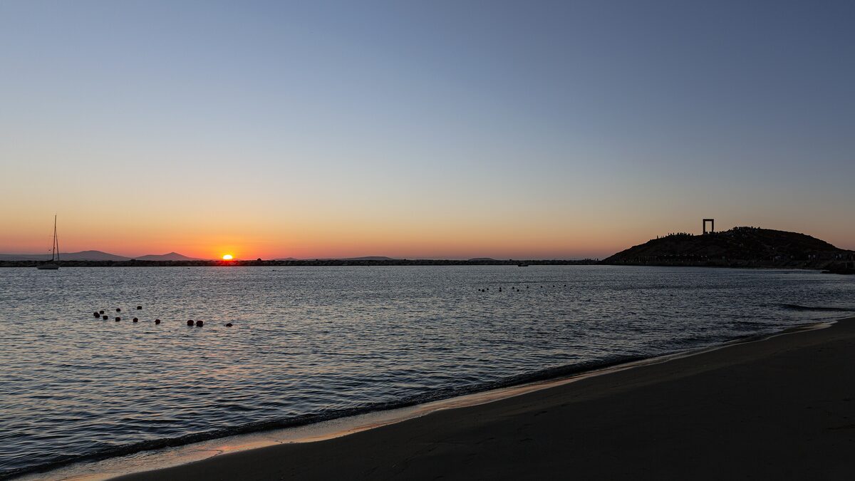 Sunset over the sea on Naxos, with the Portara visible on the islet in the distance