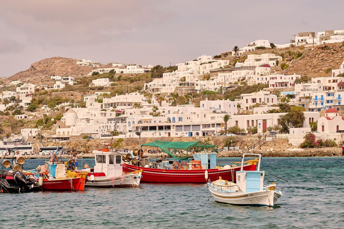 Fishing boats tied up in the harbor below the white houses of Mykonos Town