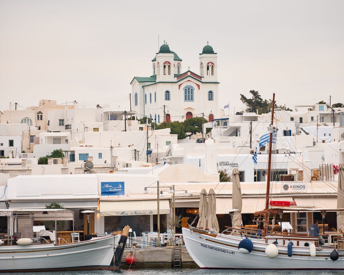 The Naoussa harbor on Paros, with white houses, a twin-towered church and wooden fishing boats at the quay