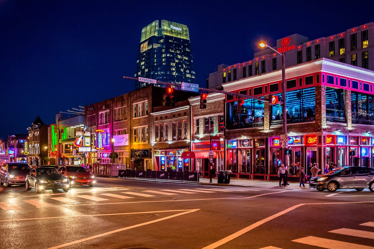 Lower Broadway at night with neon-lit honky-tonks and the downtown towers behind
