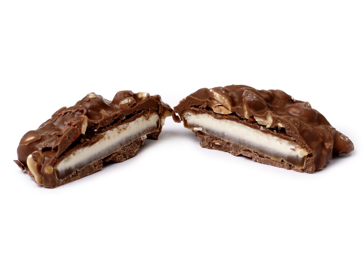 A Goo Goo Cluster broken in half to show the marshmallow and caramel layer under milk chocolate and peanuts