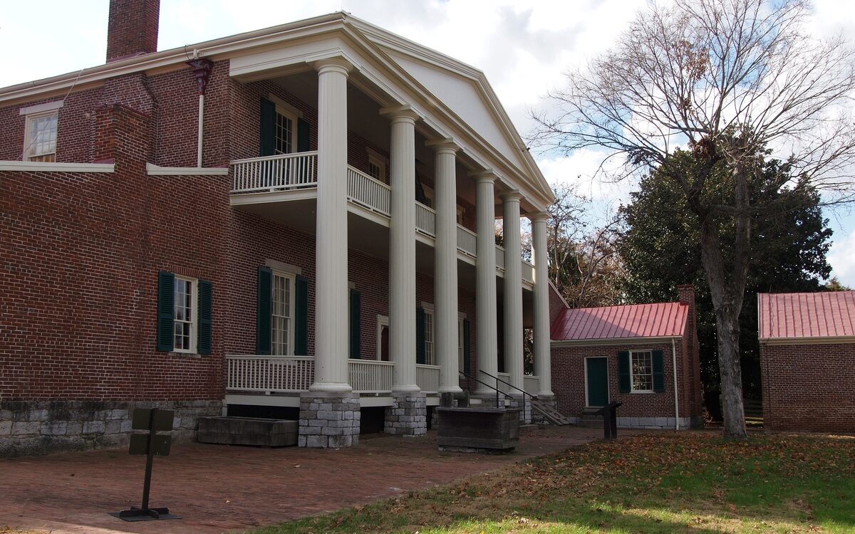 The columned two-story portico of Andrew Jackson's Hermitage mansion with brick outbuildings beside it