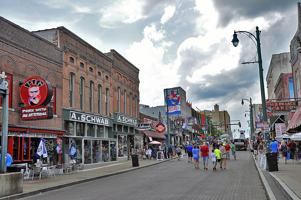 Beale Street in Memphis on a busy day, with neon signs and strolling visitors