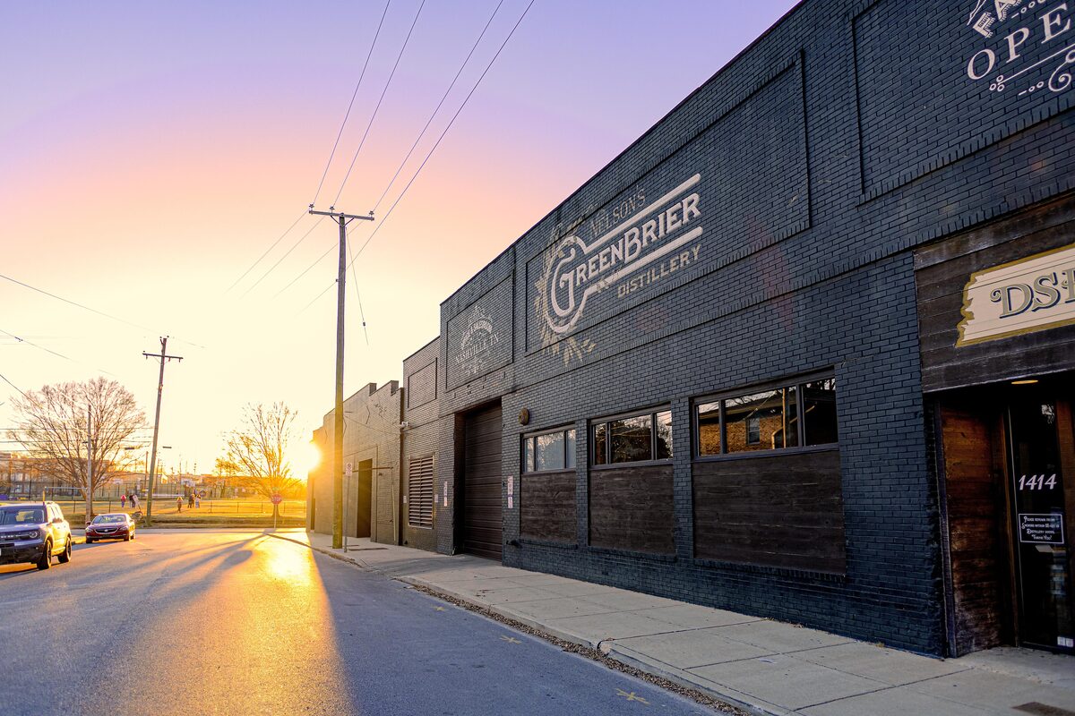 The dark brick Nelson's Green Brier Distillery building with its painted sign at sunset