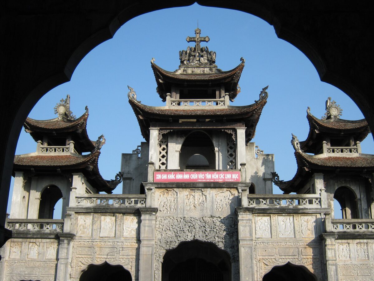 The front gate of Phat Diem Cathedral, with tiered pagoda roofs framed by a stone arch