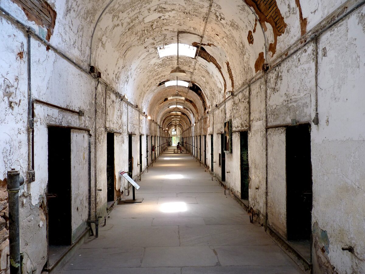 A long vaulted cell block corridor with peeling plaster at Eastern State Penitentiary