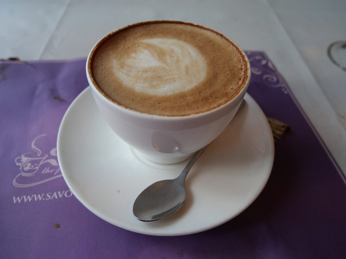 A cappuccino with latte art in a white cup and saucer