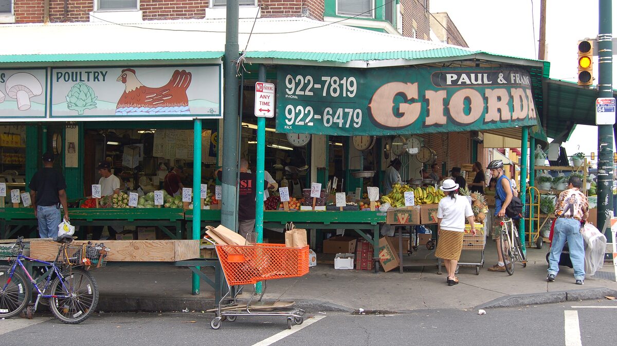 Produce stalls under green awnings on a corner of the Italian Market