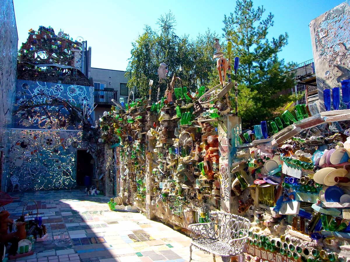 Mosaic walls of tile, bottles and bicycle wheels in a sunny courtyard at Magic Gardens
