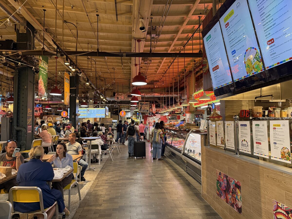Diners and food stalls under the high ceiling inside Reading Terminal Market