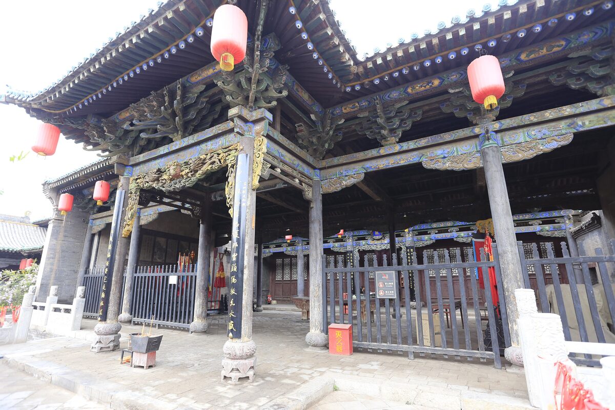 An open timber pavilion with red lanterns and carved eaves in the Pingyao City God Temple