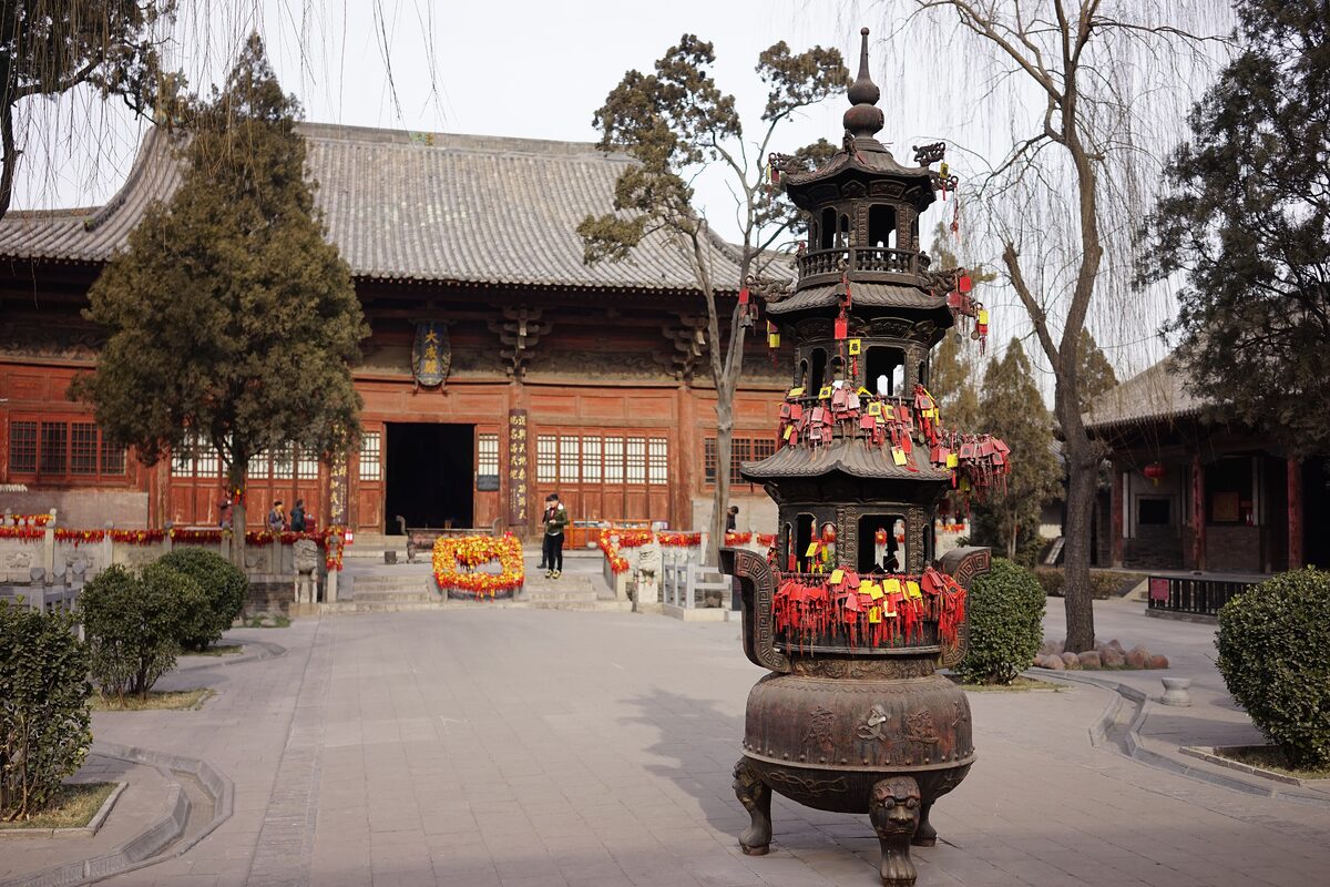 The red-timbered main hall of the Pingyao Confucian Temple behind a tiered incense burner