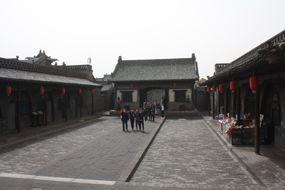 The main courtyard of the Pingyao county government office, with a gate hall at the far end and visitors walking in