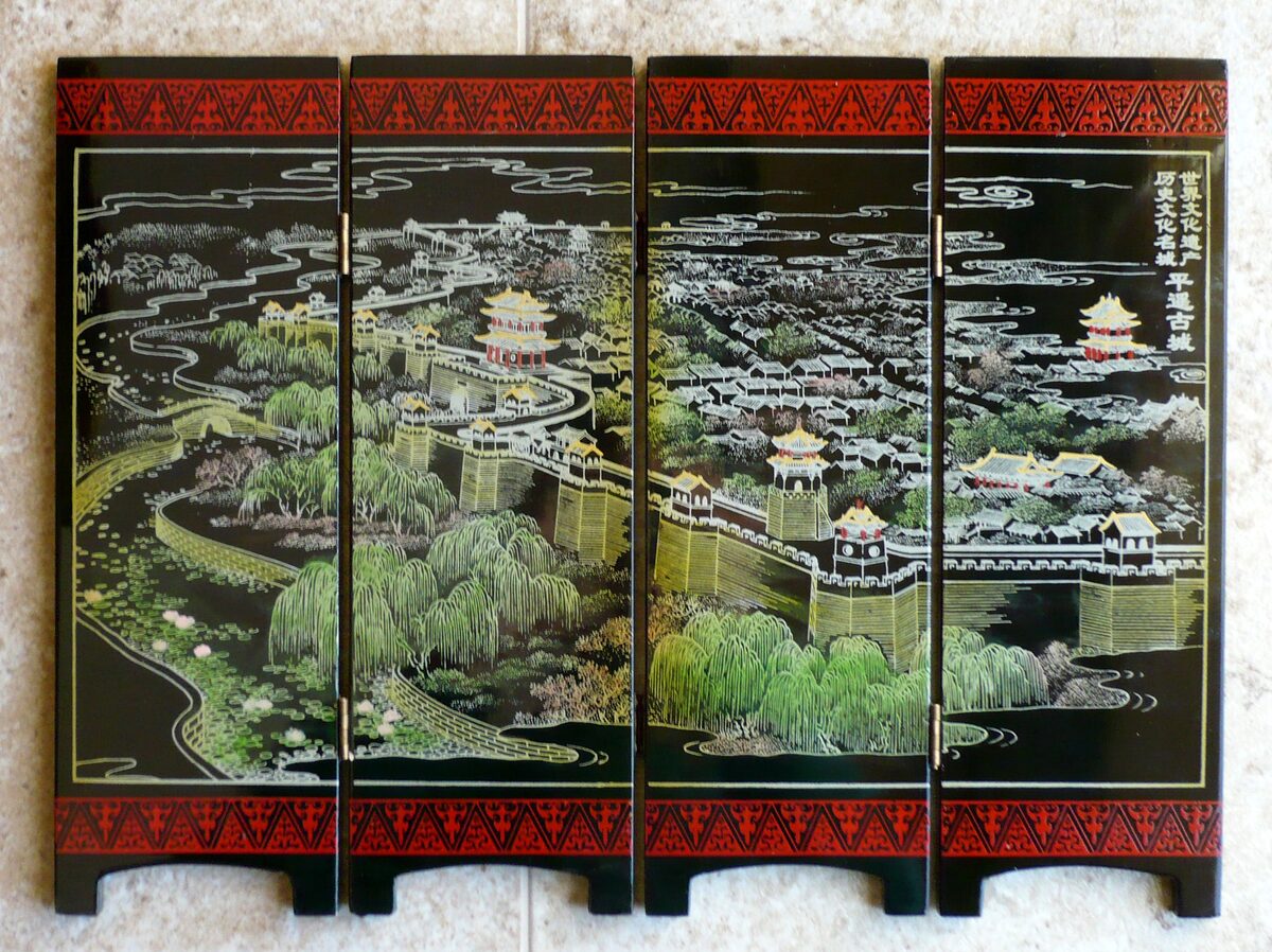 A black four-panel lacquer screen with a silver and green painting of the Pingyao walls and rooftops