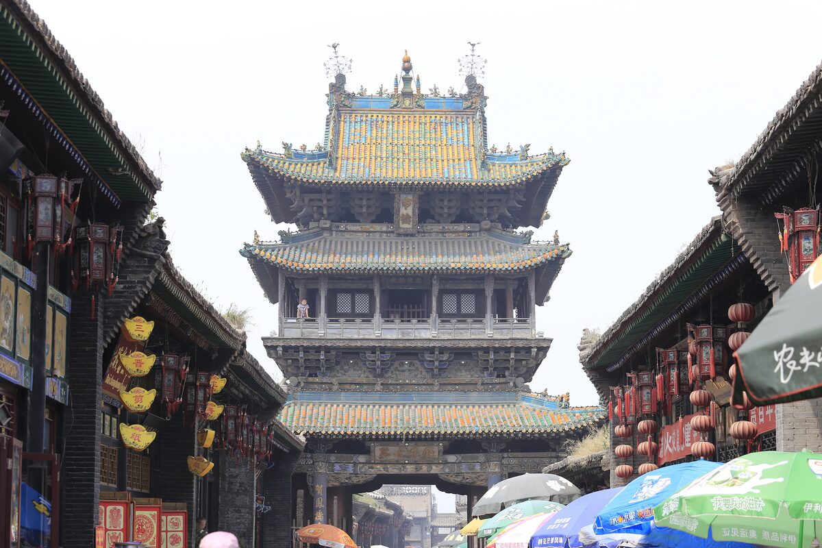 The three-tiered Market Tower with yellow and green glazed roofs rising above the red-lantern shopfronts of the main street