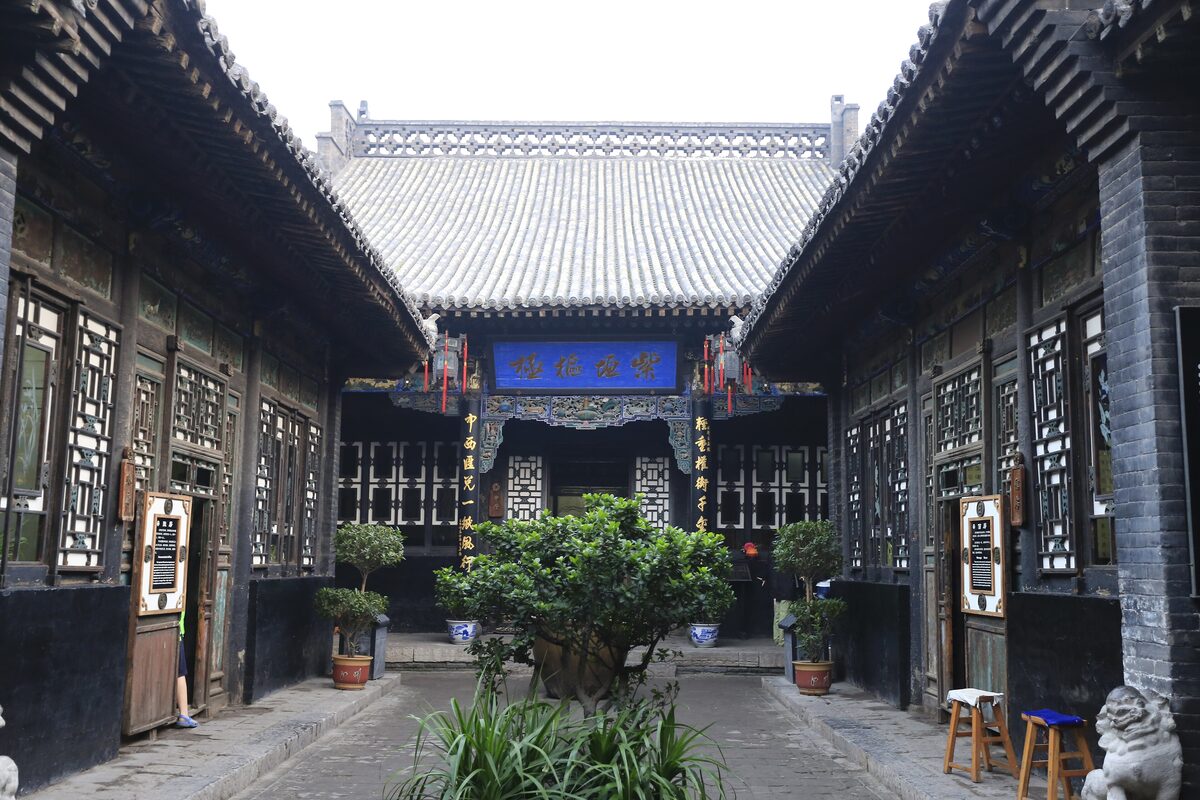 A paved courtyard at the former Rishengchang bank, with carved wooden lattice windows and a hall at the end
