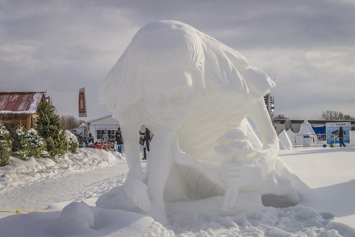 A huge snow sculpture at the Quebec Winter Carnival, with snowy paths and visitors beyond
