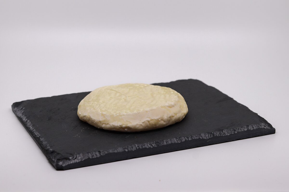 A round pale soft cheese, the Paillasson de l'Isle d'Orléans, on a slate board