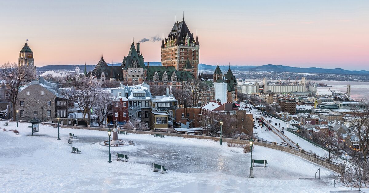 The Château Frontenac and the snow-covered roofs of Old Quebec at dusk, with the frozen St. Lawrence River beyond
