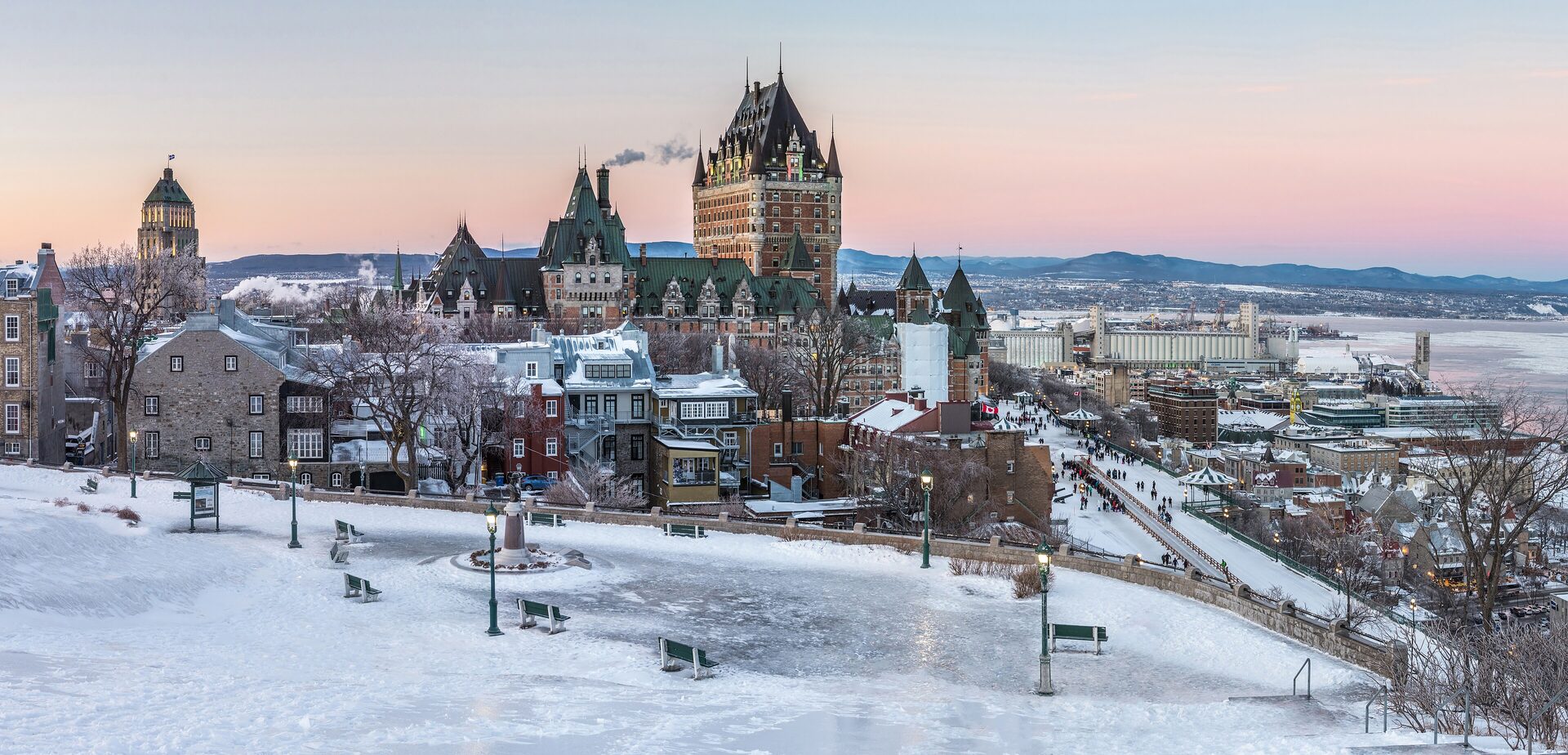 The Château Frontenac and the snow-covered roofs of Old Quebec at dusk, with the frozen St. Lawrence River beyond